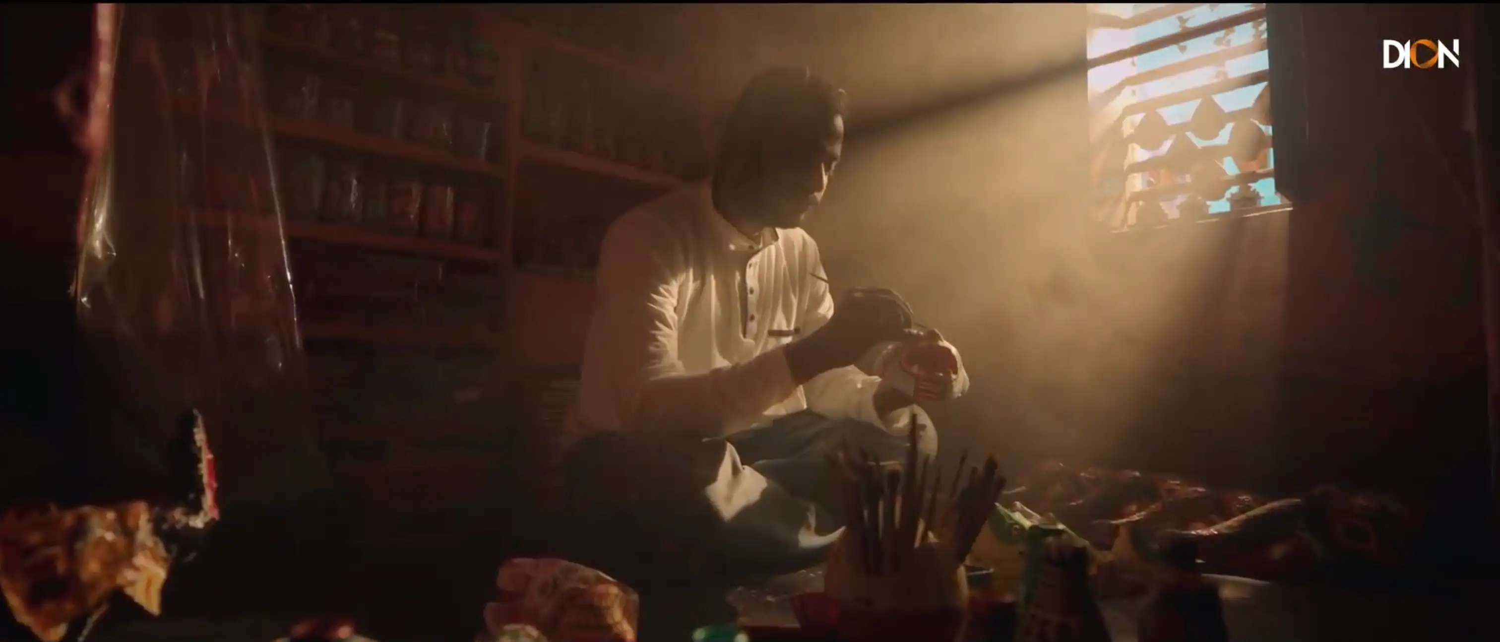 An artisan working by hand beneath a warm beam of window light in the DION brand film