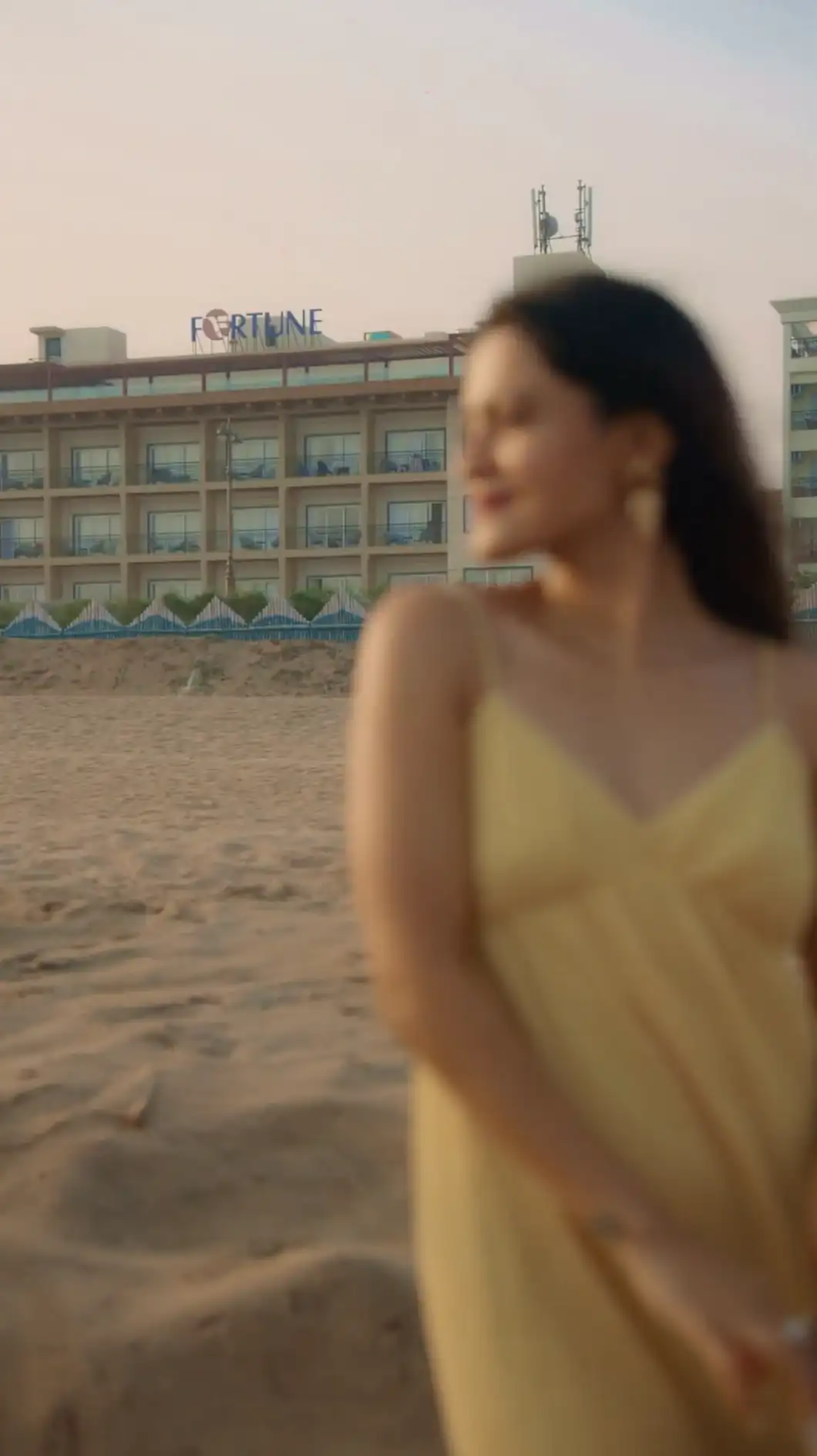 Woman in a yellow dress on Puri beach with Fortune Beachfront Puri behind her