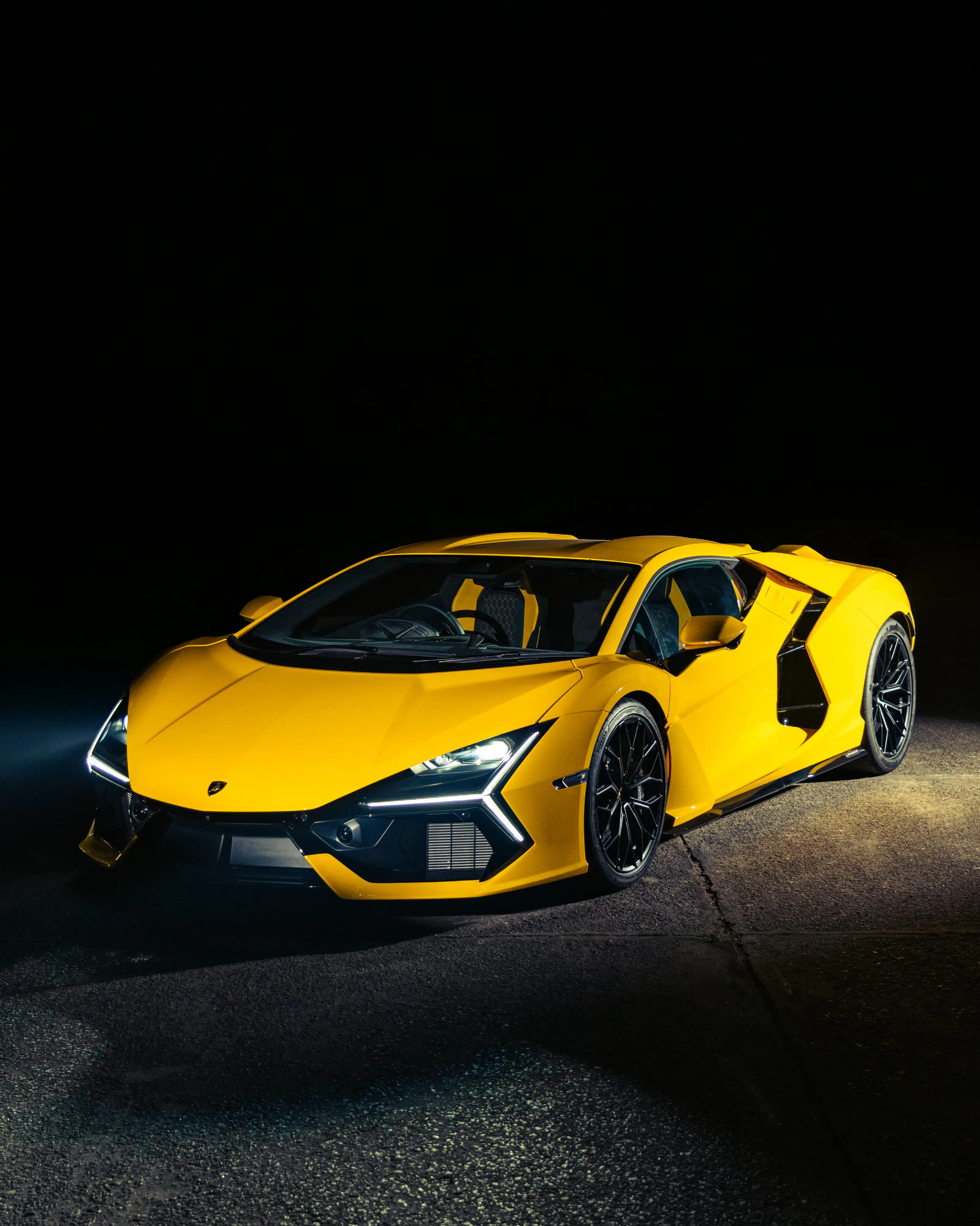 Yellow Lamborghini Revuelto illuminated on a dark road at night