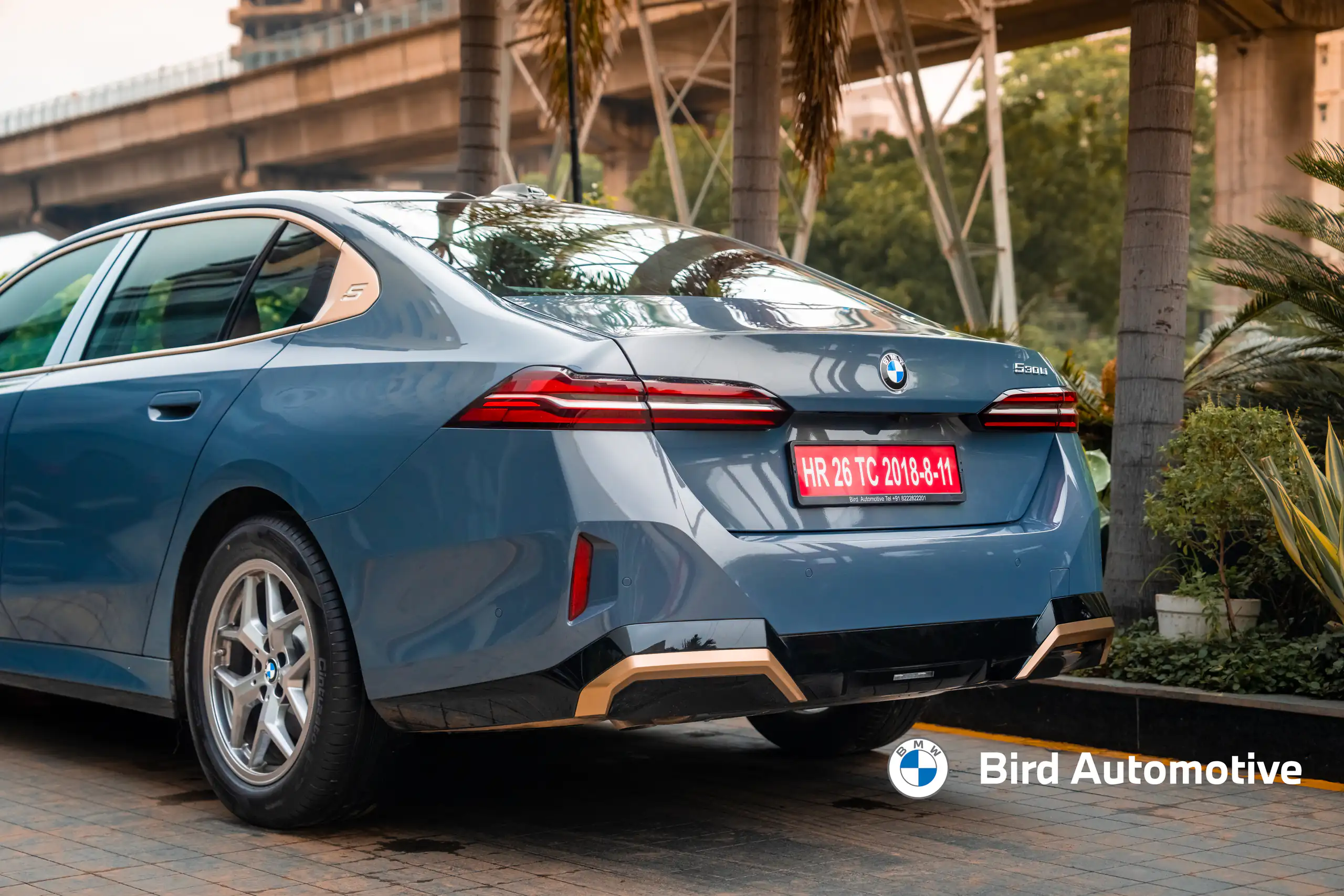 Rear three-quarter view of a blue BMW sedan outside a dealership