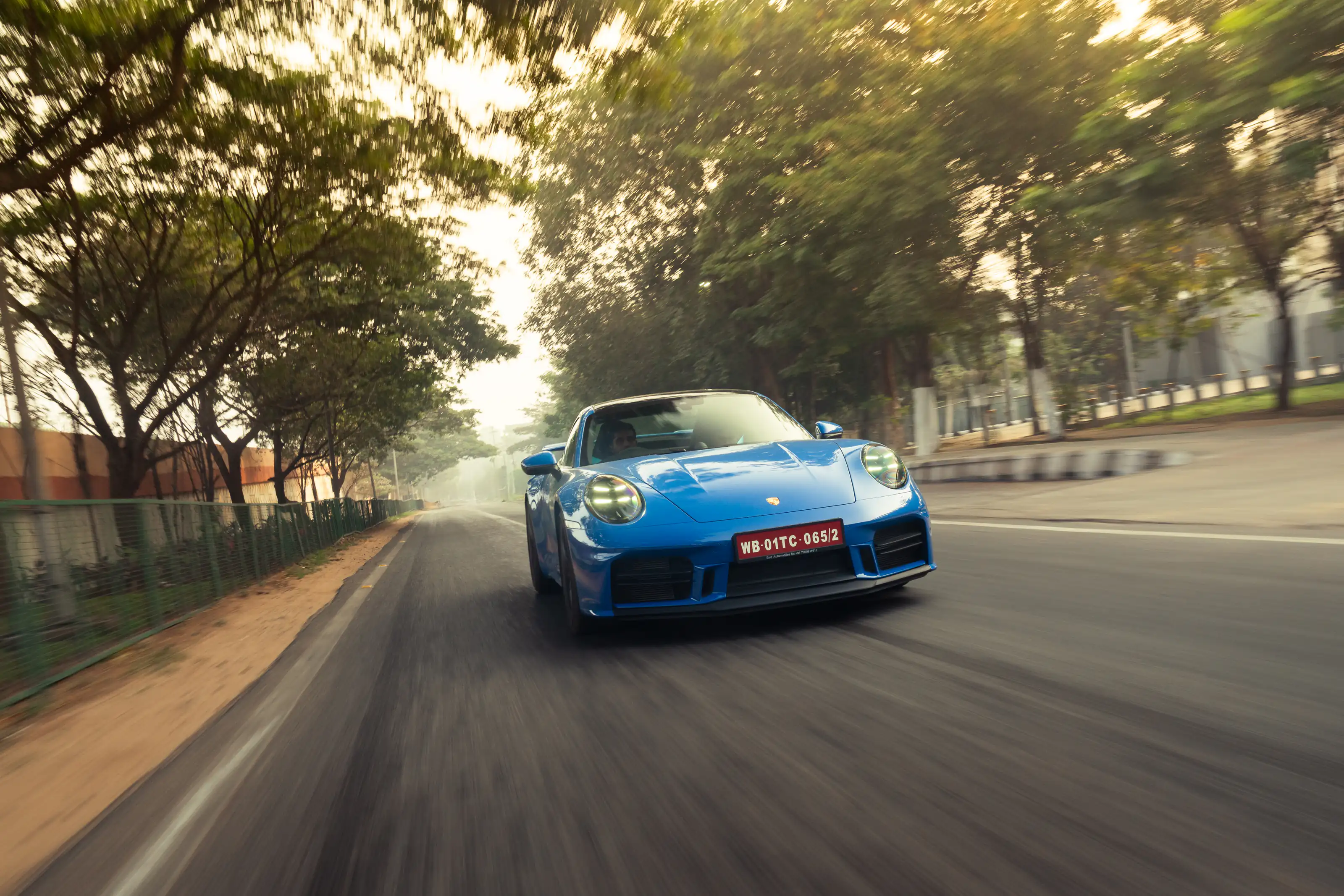 Blue Porsche photographed at speed on a tree-lined road