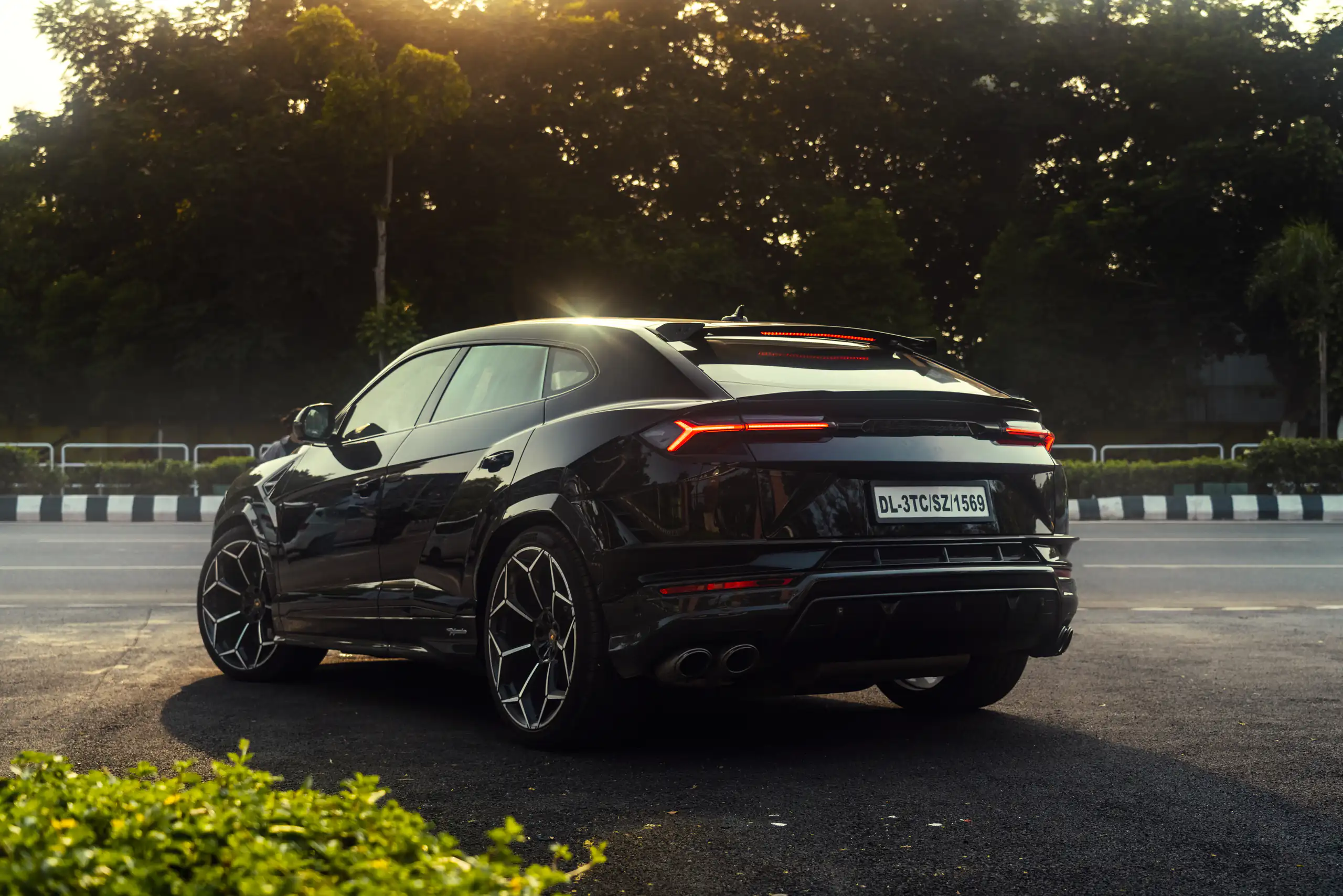 Black Lamborghini Urus caught in profile beneath a burst of sunlight