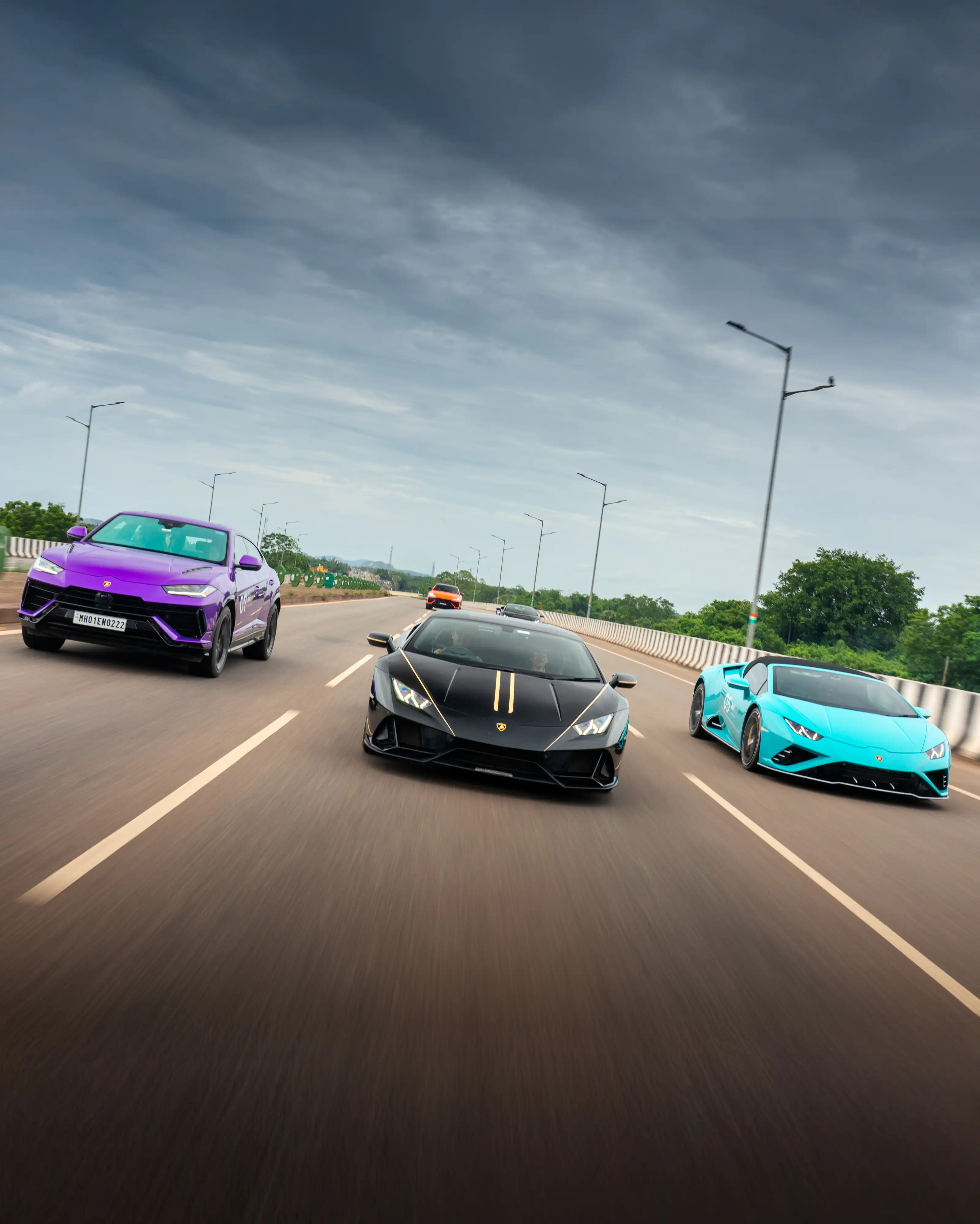 Three Lamborghinis driving abreast beneath an open sky