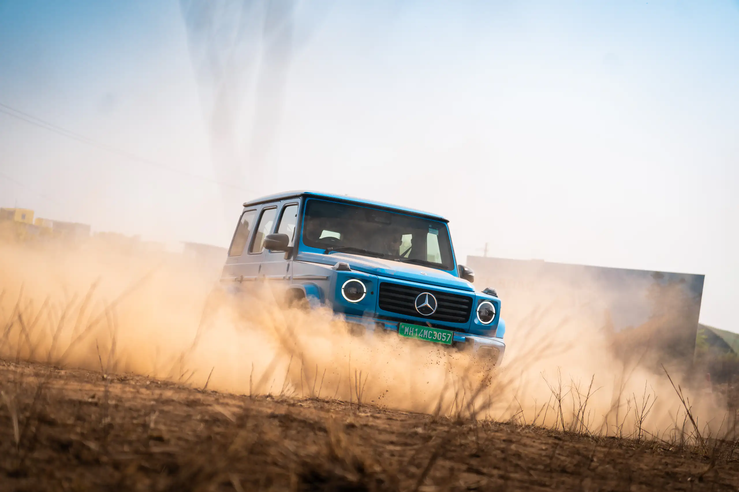 Blue Mercedes-Benz G-Class driving through an off-road dust trail