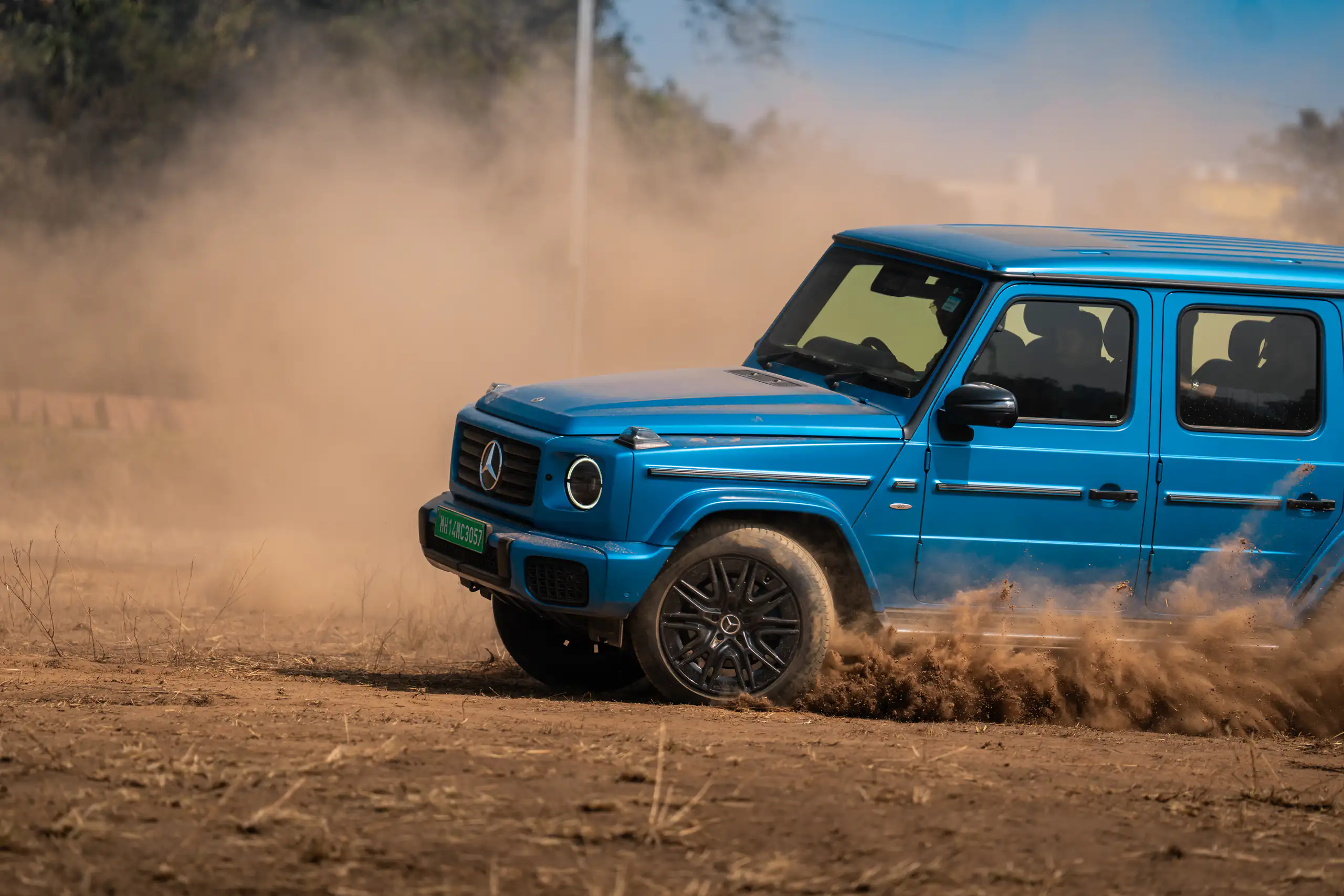 Blue Mercedes-Benz G-Class travelling through a dusty off-road landscape