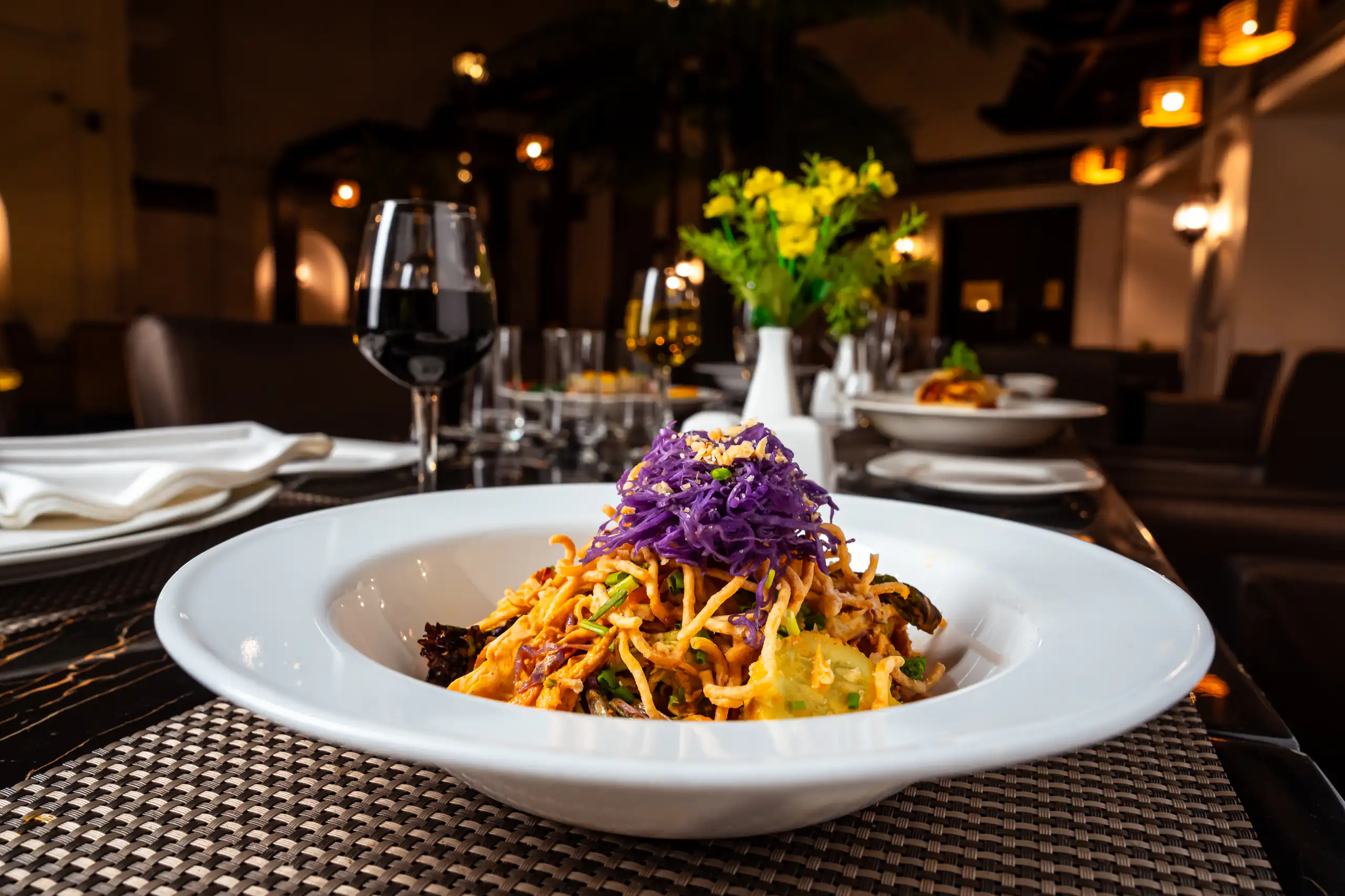 Plated noodles framed by a warmly lit dining room