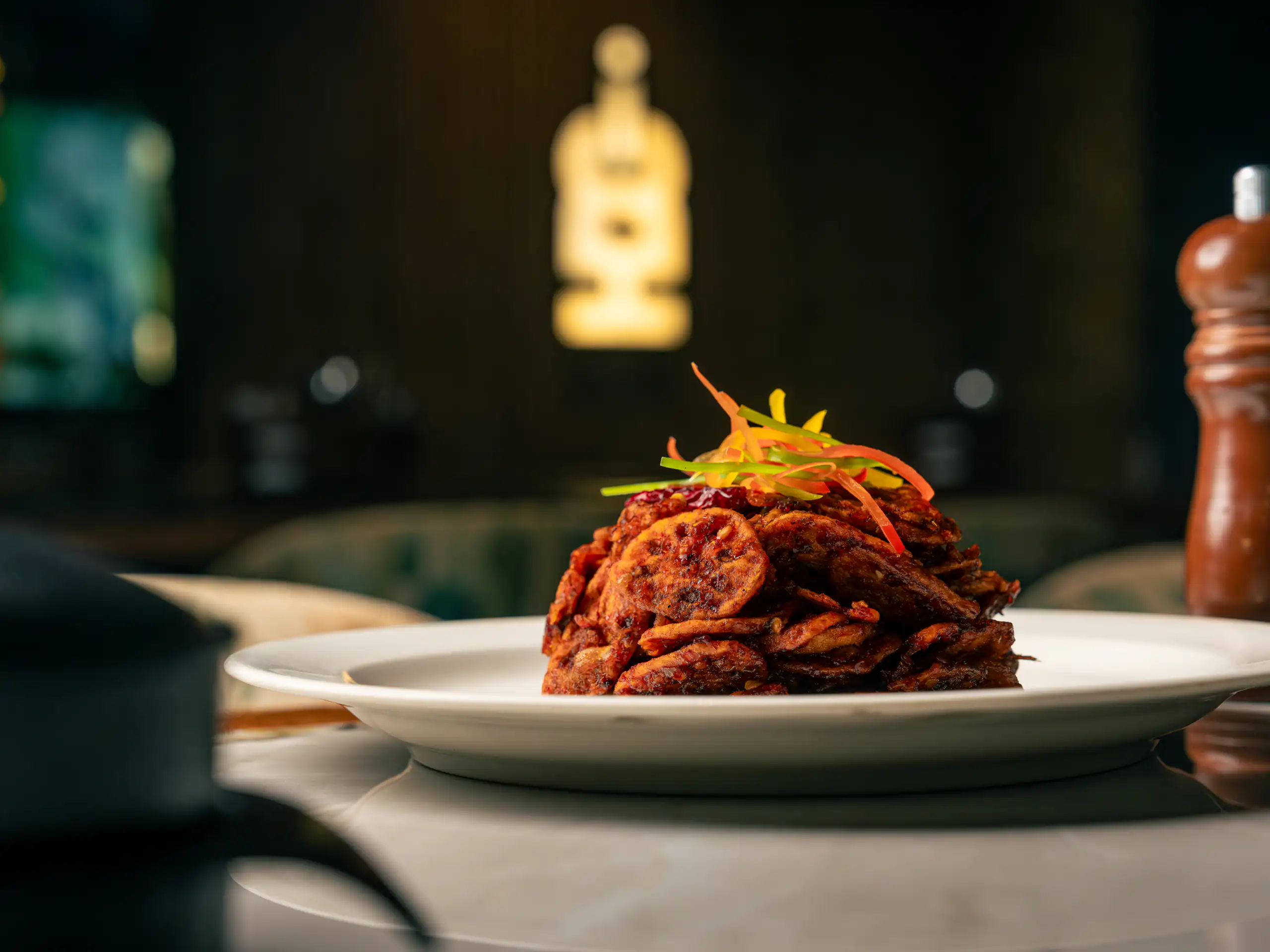 Stacked spiced fritters plated in a dark restaurant interior