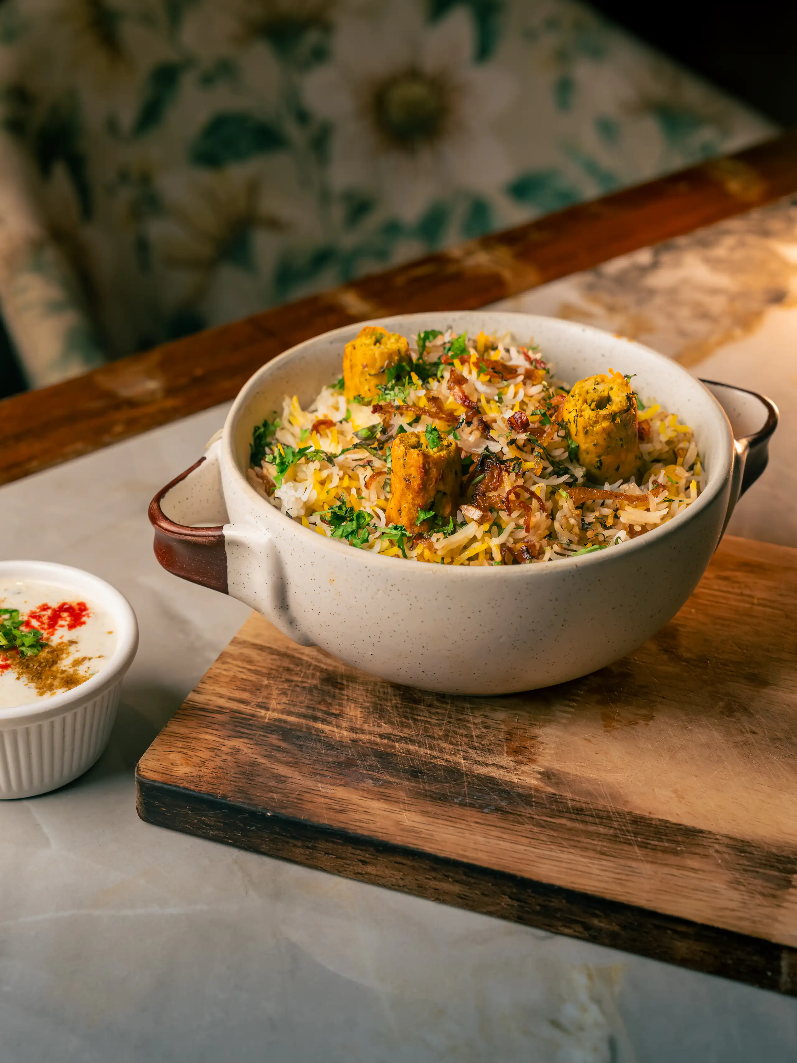 Generous biryani pot surrounded by condiments on a wooden table