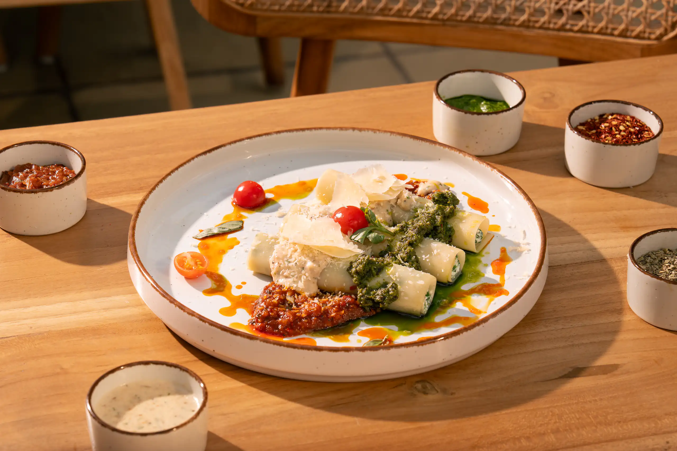 Plated pasta with pesto and parmesan on a bright wooden table