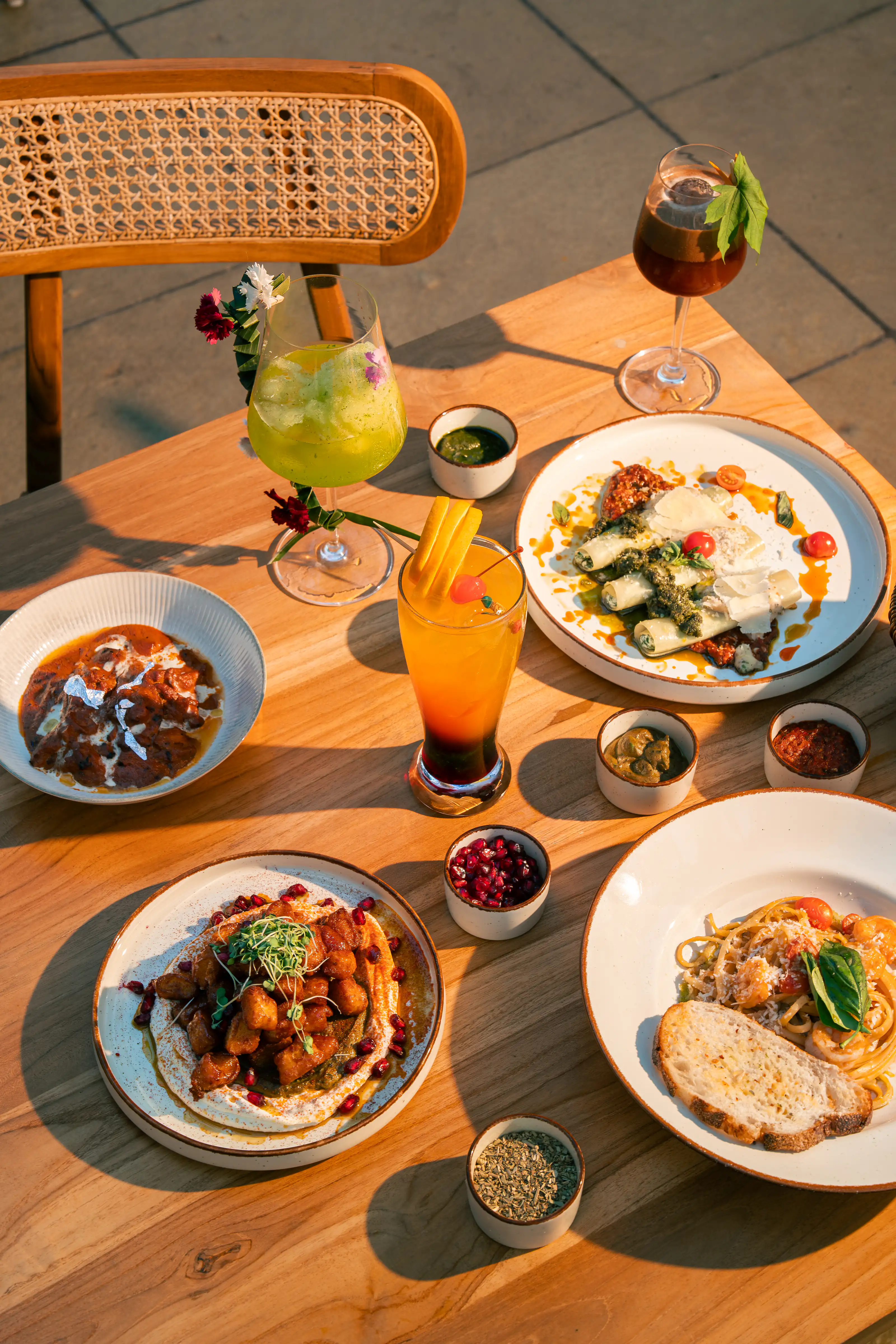 Overhead spread of colourful dishes and drinks in warm afternoon light