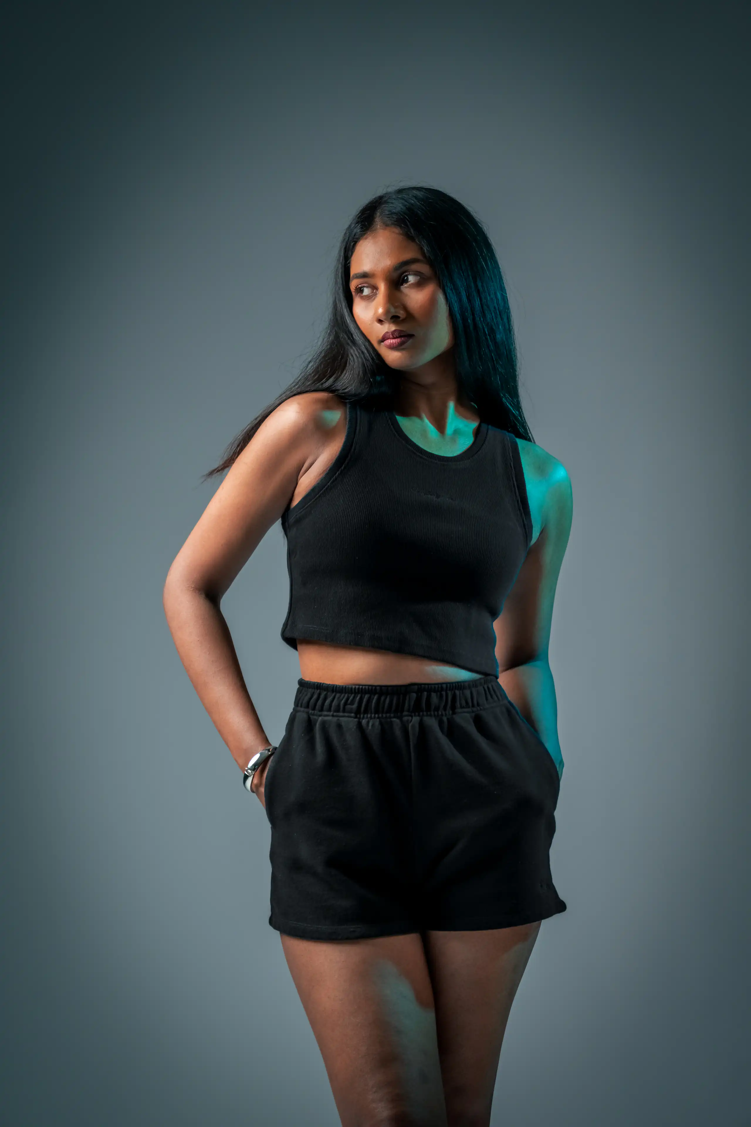 Woman in a black sleeveless top lit with a teal studio accent