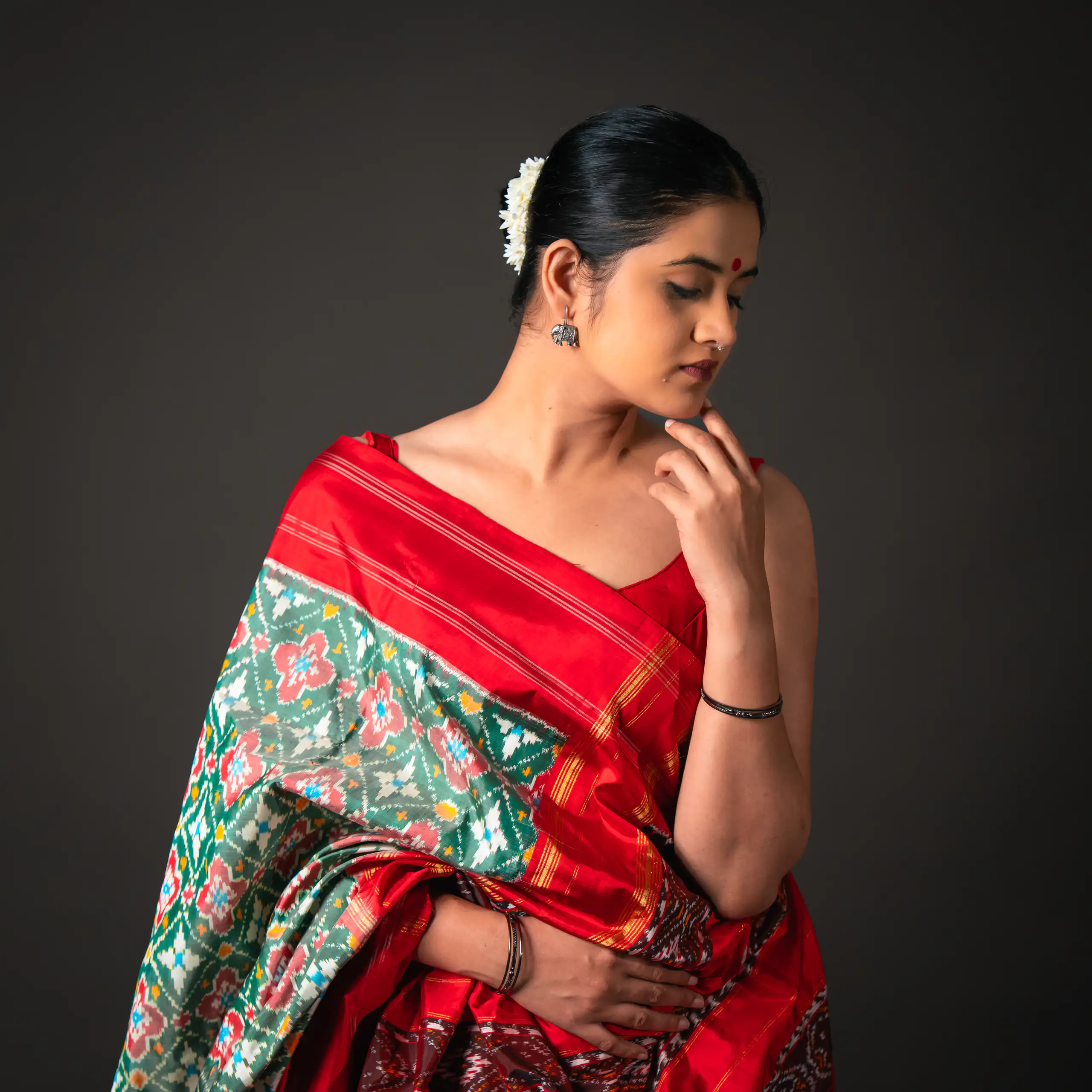 Studio portrait of a woman draped in a red and turquoise patterned sari