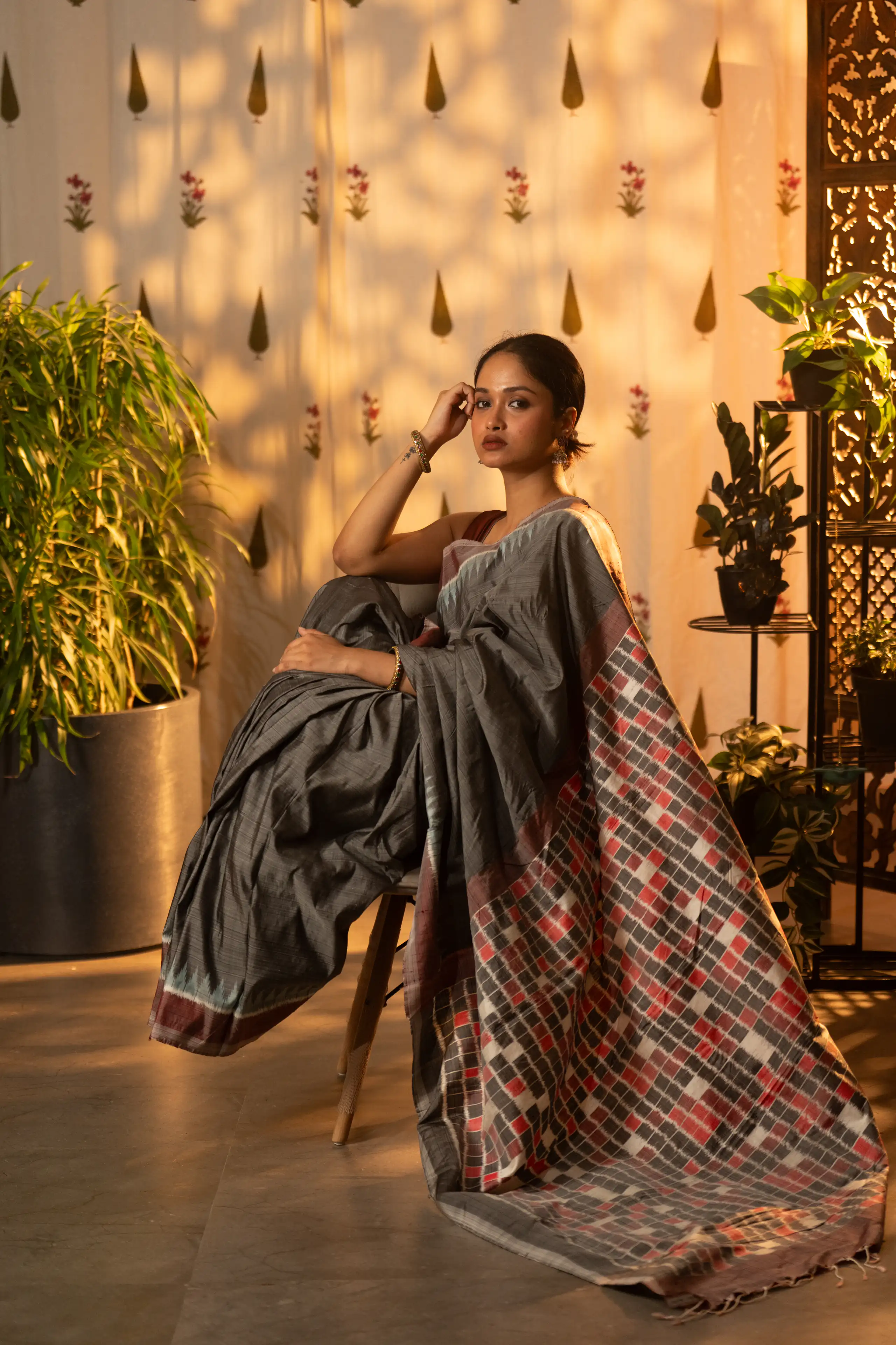 Woman wearing a patterned sari posed in a warmly lit interior