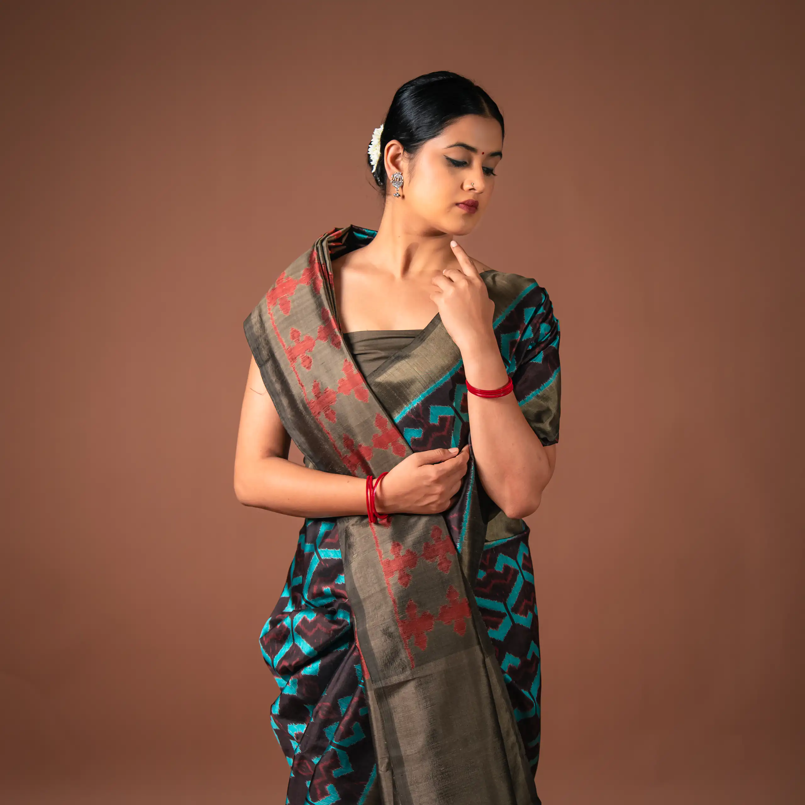 Fashion portrait of a woman in a patterned sari against terracotta