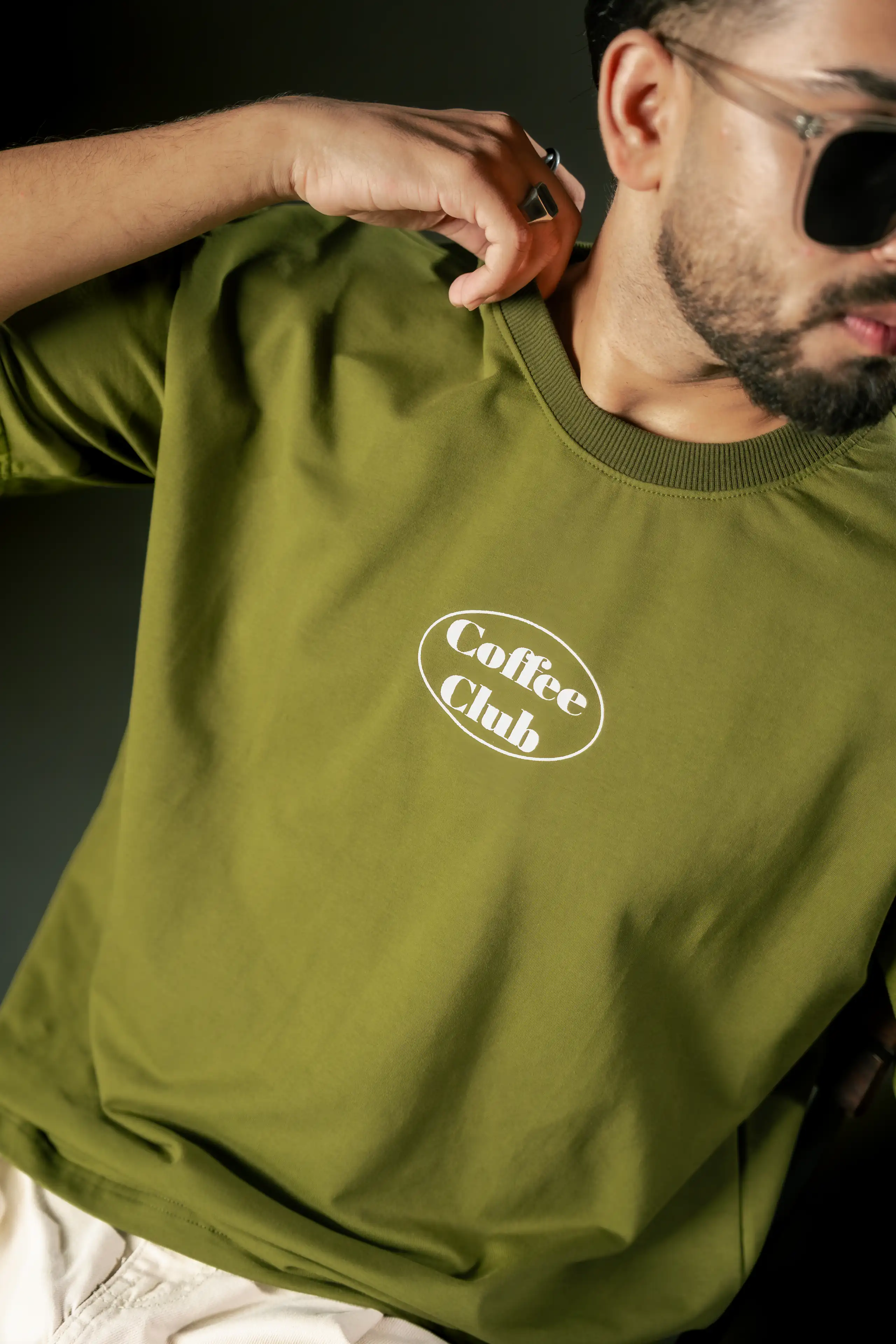 Close crop of a model wearing an olive Coffee Club T-shirt