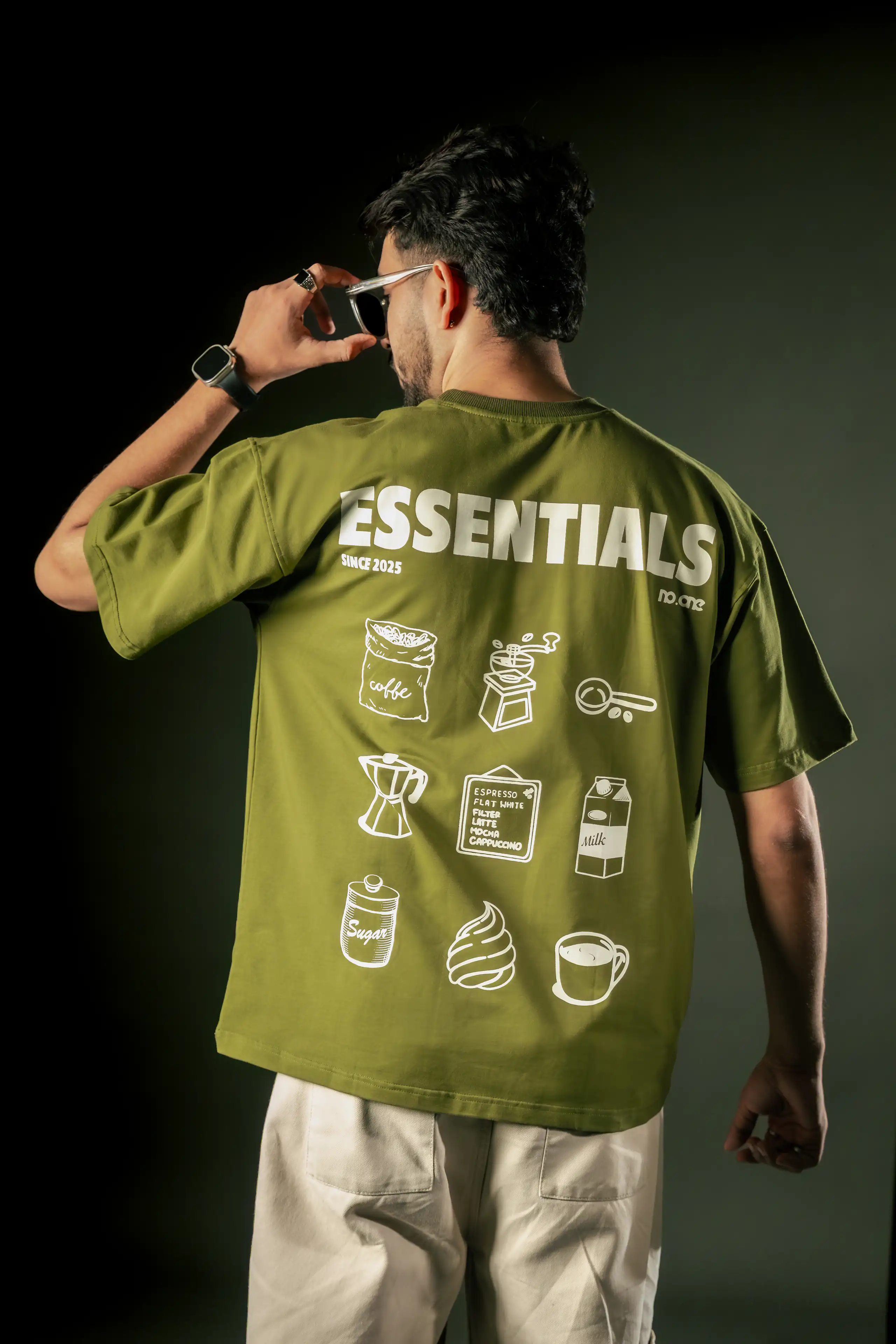 Model showing the illustrated back of an oversized olive T-shirt
