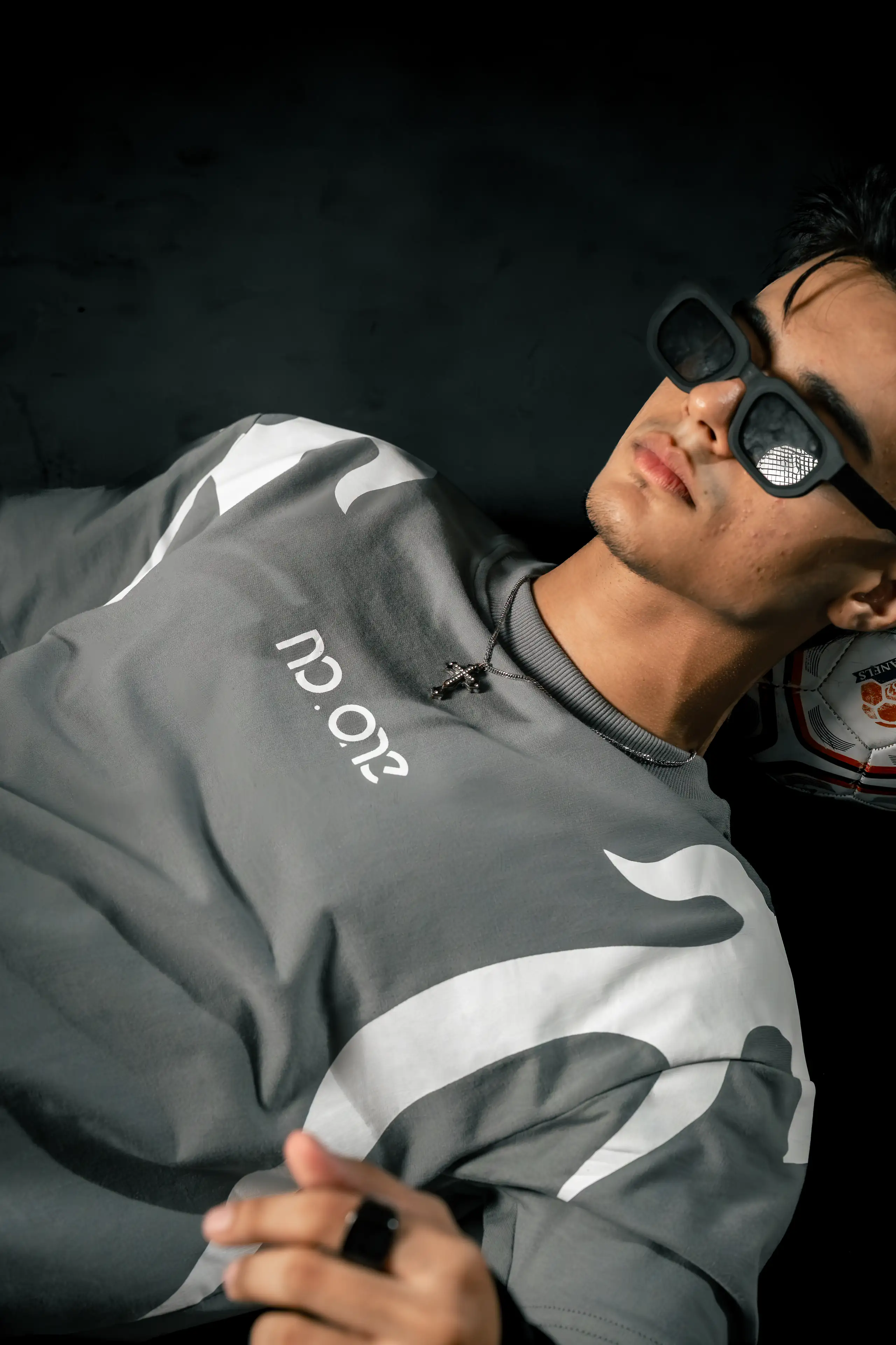 Model in sunglasses reclining in a monochrome sweatshirt