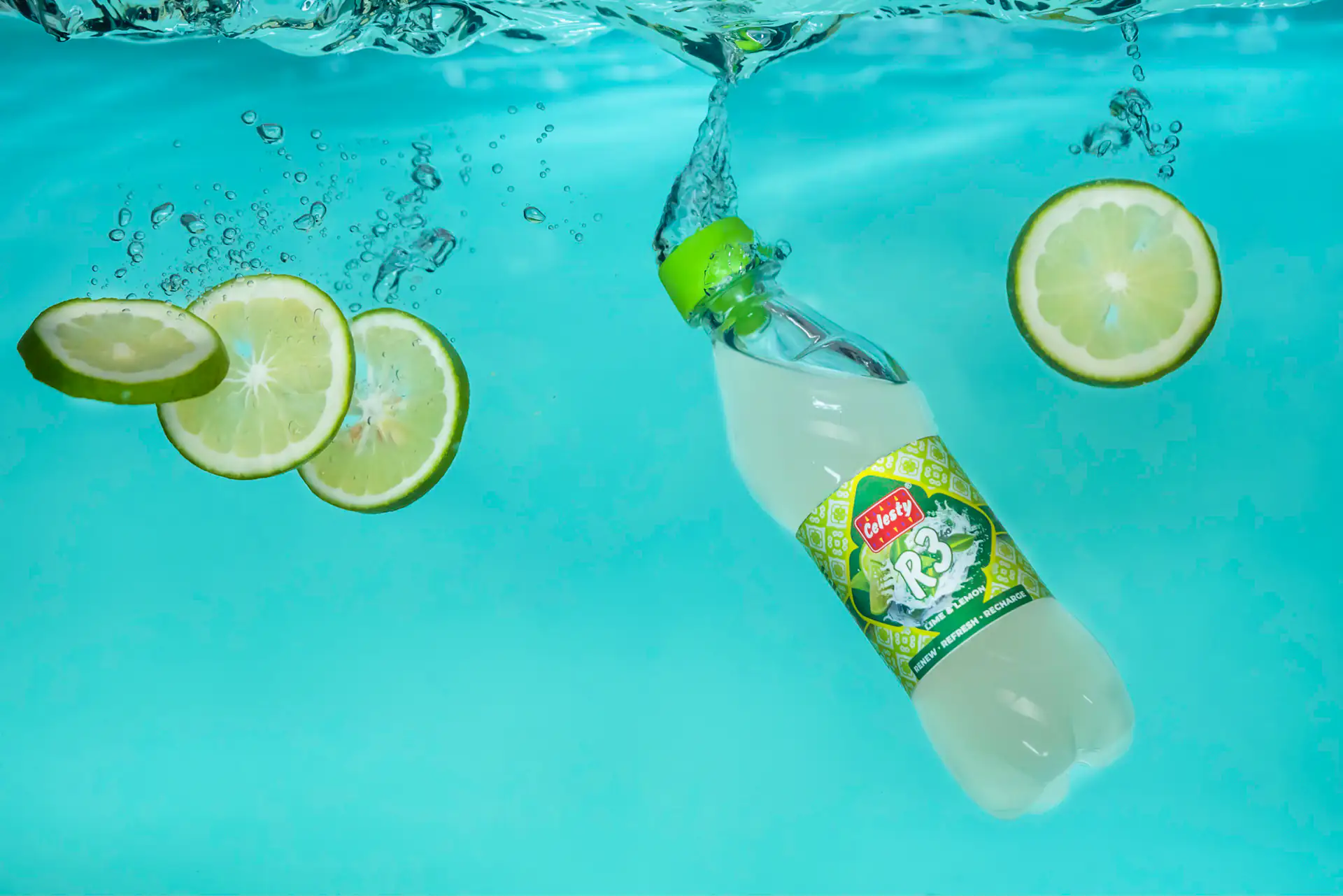 Lime soda bottle suspended underwater with lime slices and bubbles
