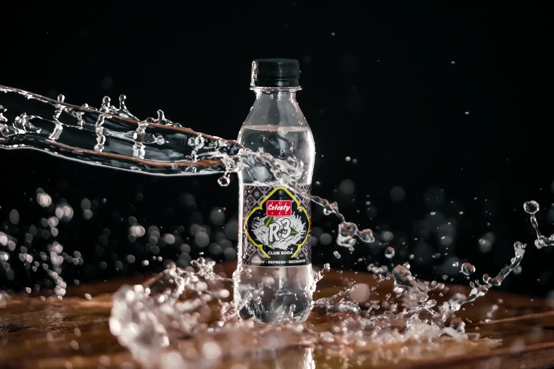Club soda bottle surrounded by a suspended arc of water on black