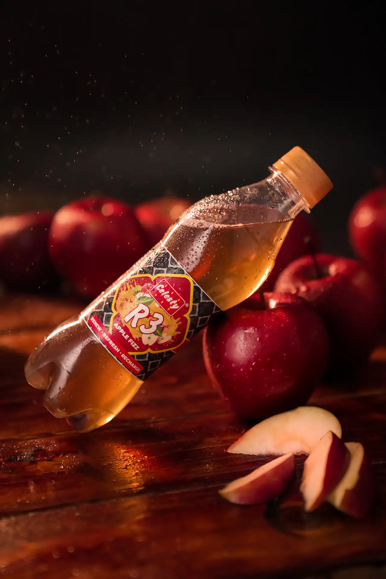 Apple soda bottle tilted among red apples in dramatic warm light