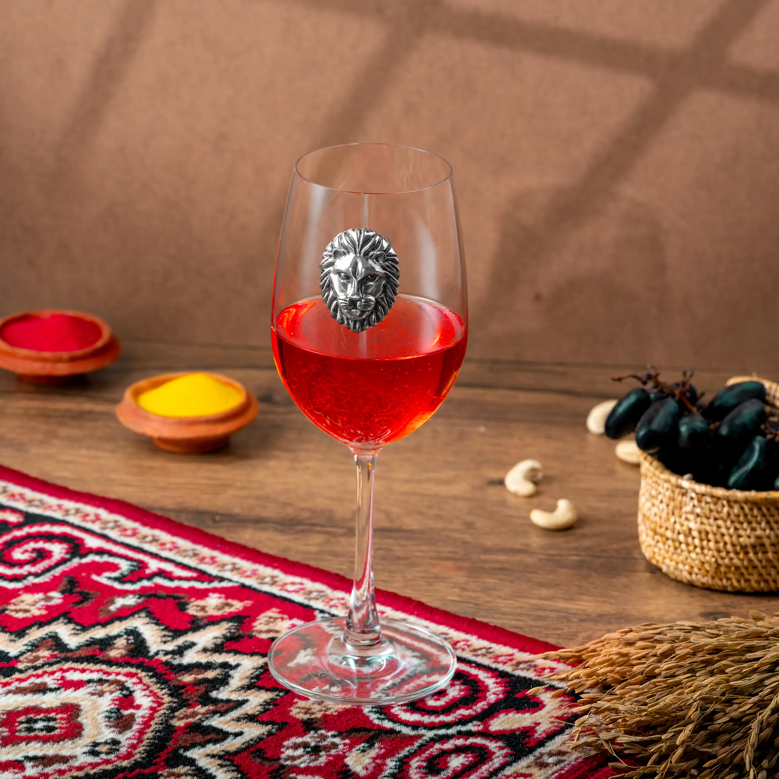 Red drink in a stemmed glass with an eagle emblem styled on a richly patterned table