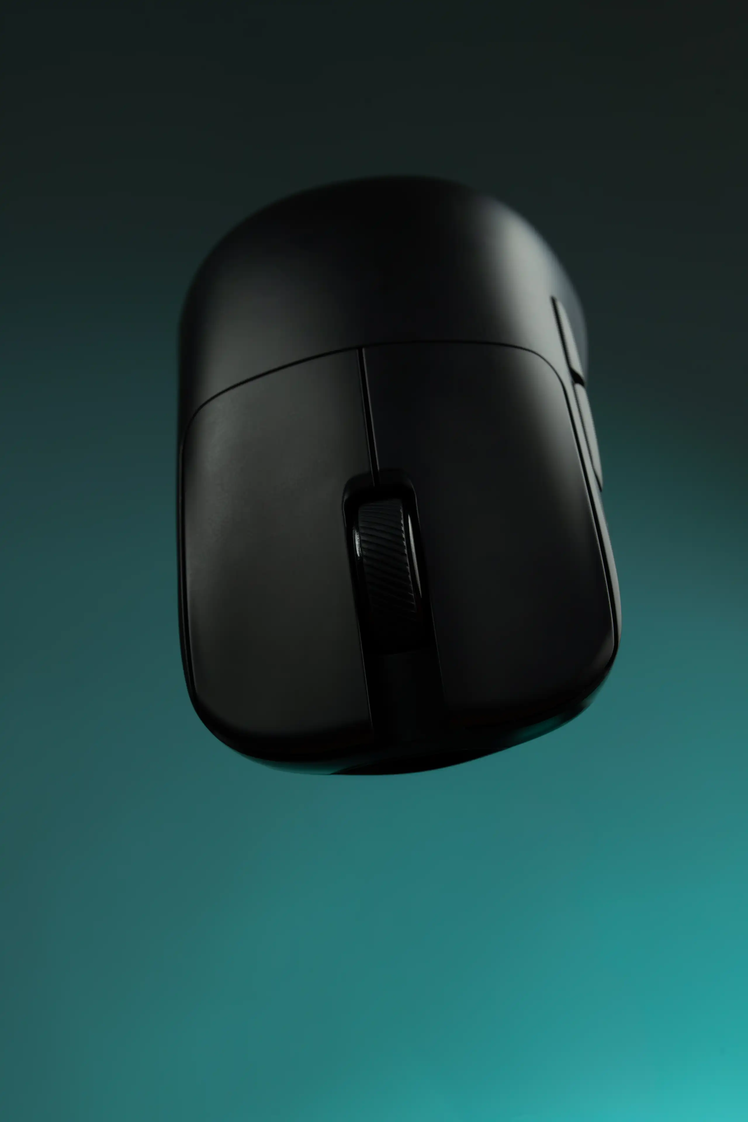 Black computer mouse photographed against a teal gradient