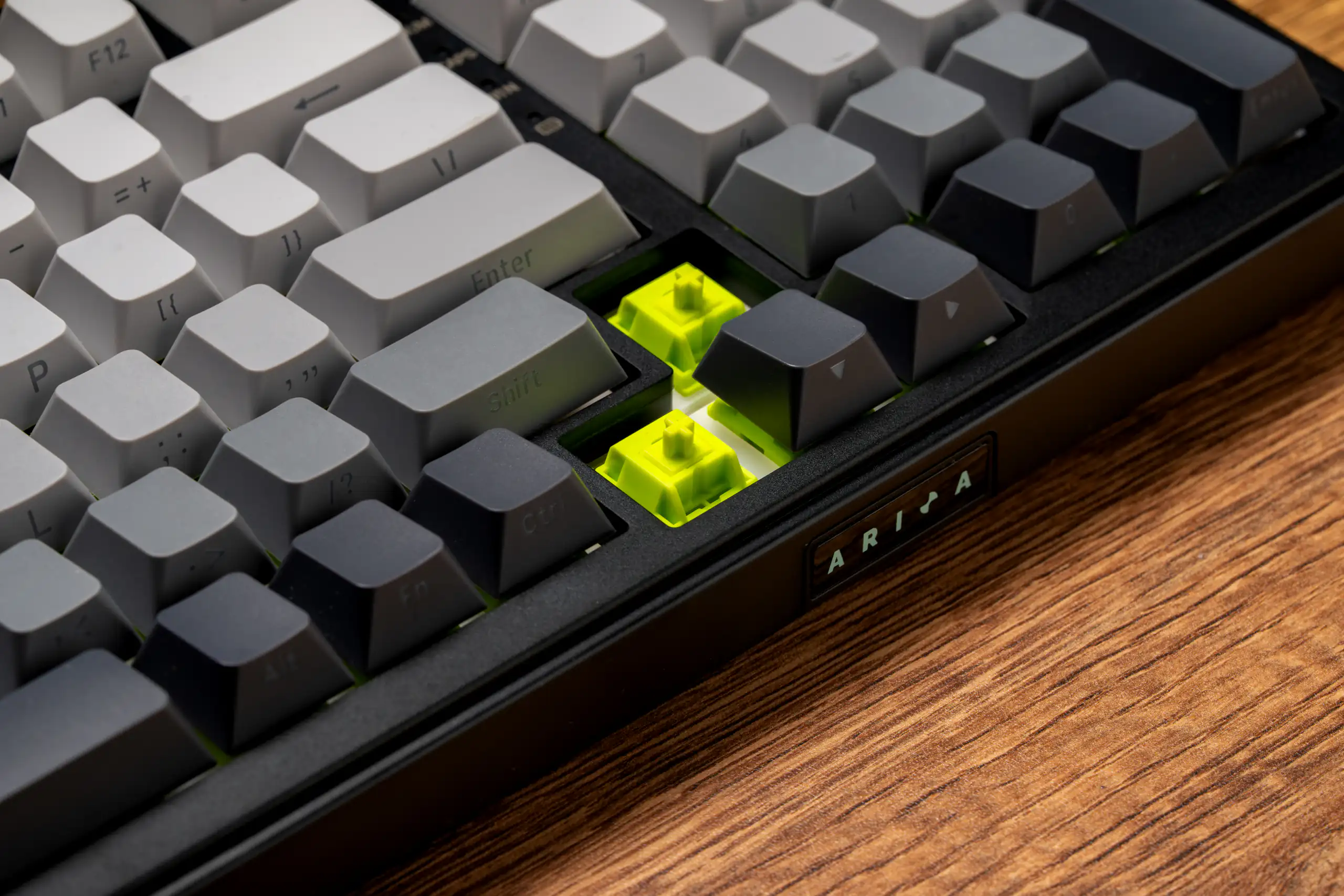 Mechanical keyboard with translucent neon green accent keys on a wooden desk