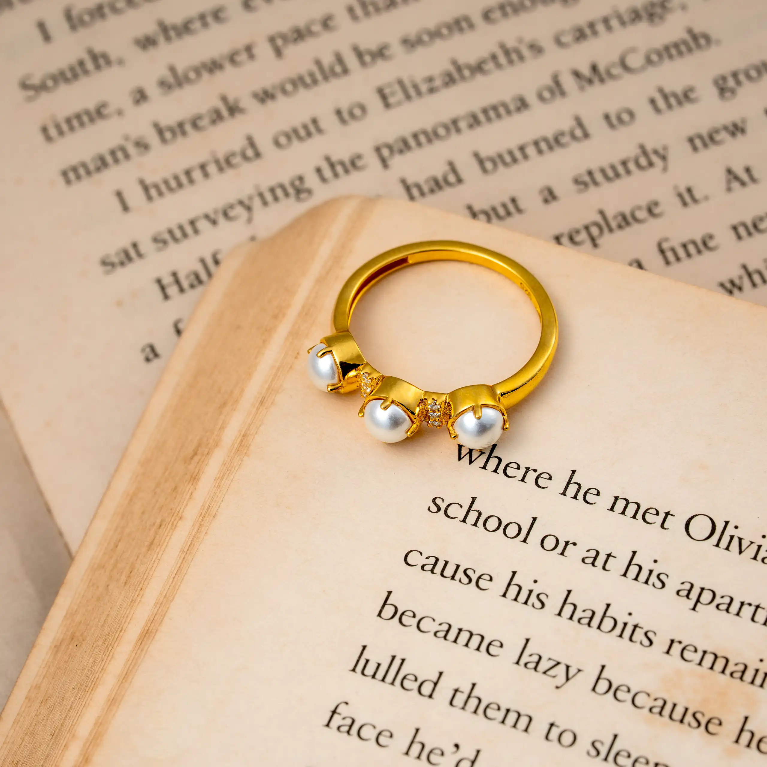 Gold ring with small white stones arranged on the page of an open book