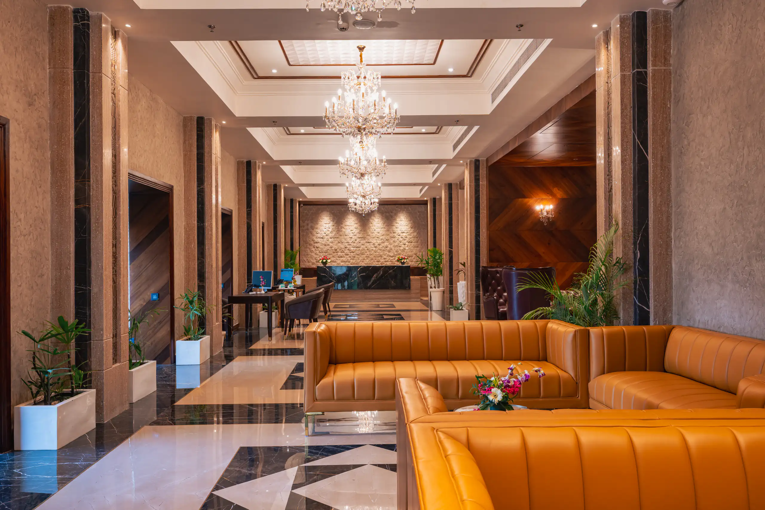 Hotel lobby with chandeliers, polished stone and caramel leather seating