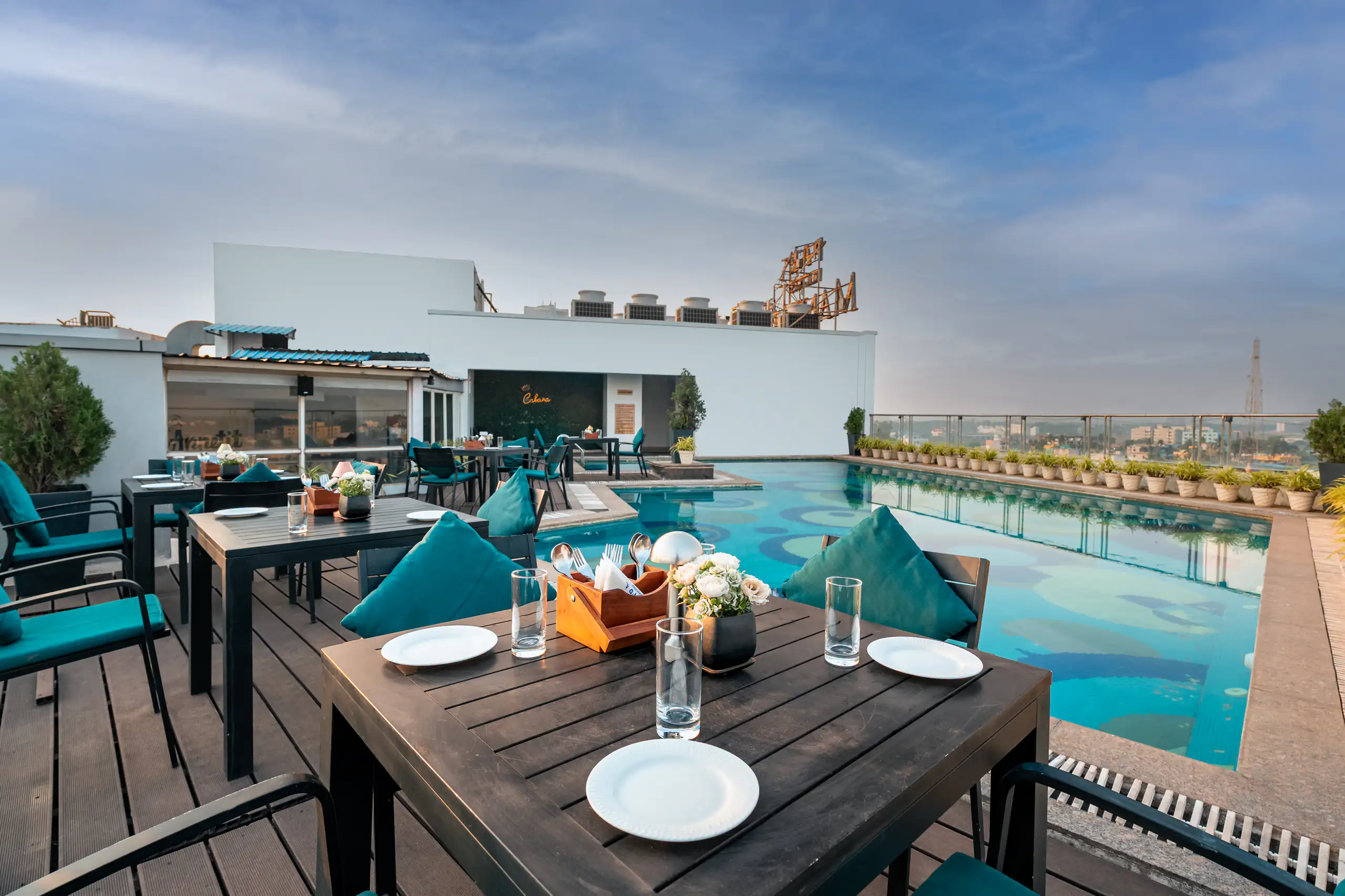 Rooftop poolside restaurant beneath a broad blue sky