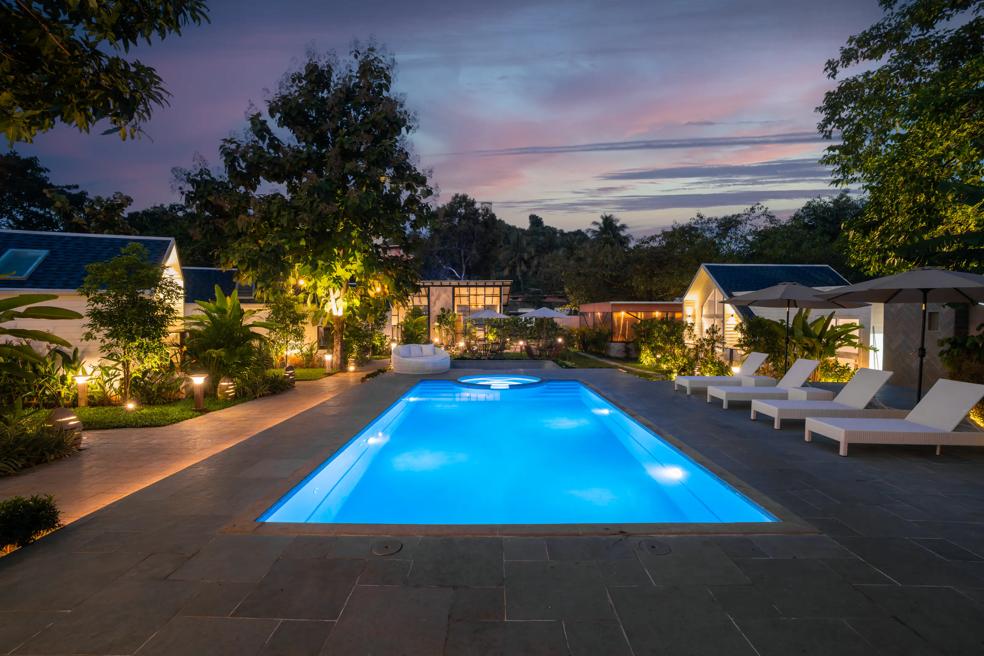 Illuminated resort pool and garden cottages at blue hour
