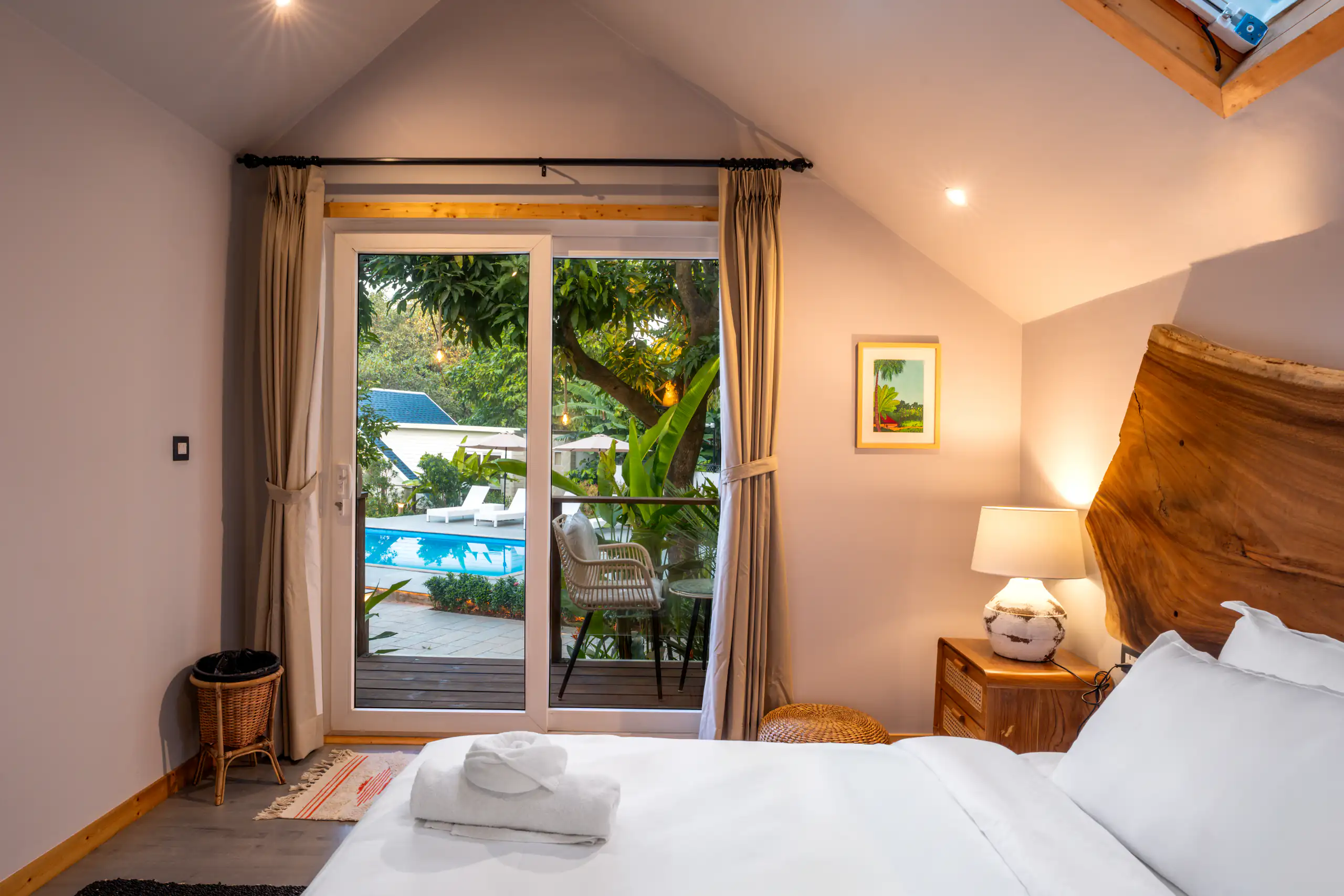 Warmly lit resort bedroom with a balcony overlooking the pool